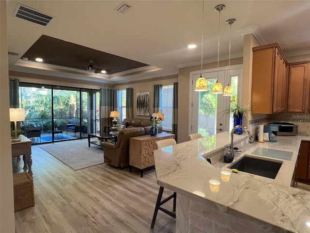 5031 Serata Dr, Bradenton, FL 34211 - kitchen featuring a tray ceiling, visible vents, a sink, and light wood finished floors
