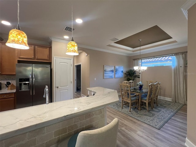 5031 Serata Dr, Bradenton, FL 34211 - kitchen featuring stainless steel fridge, visible vents, arched walkways, brown cabinets, and wood finished floors