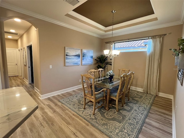 5031 Serata Dr, Bradenton, FL 34211 - dining space featuring arched walkways, a tray ceiling, baseboards, and light wood-style floors
