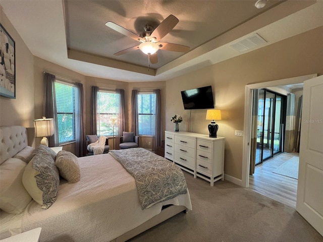 5031 Serata Dr, Bradenton, FL 34211 - bedroom featuring a tray ceiling, visible vents, a ceiling fan, light carpet, and baseboards