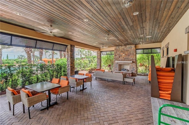 5031 Serata Dr, Bradenton, FL 34211 - sunroom / solarium with an outdoor stone fireplace, wood ceiling, and a ceiling fan