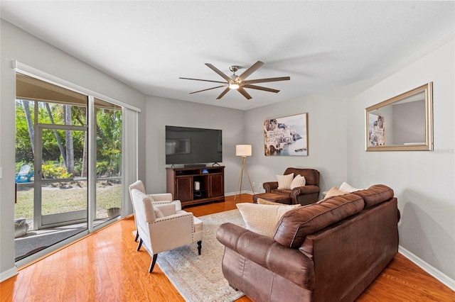 living room featuring ceiling fan, baseboards, and wood finished floors