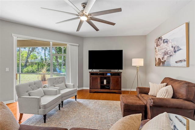 living room featuring ceiling fan, baseboards, and wood finished floors