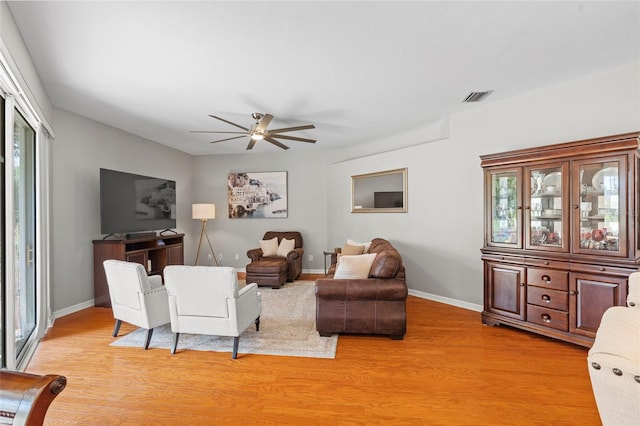 living area featuring light wood finished floors, a ceiling fan, visible vents, and baseboards