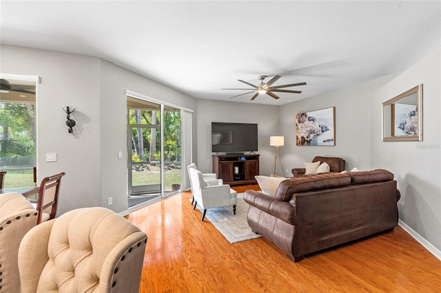 living room with light wood finished floors, baseboards, and a ceiling fan