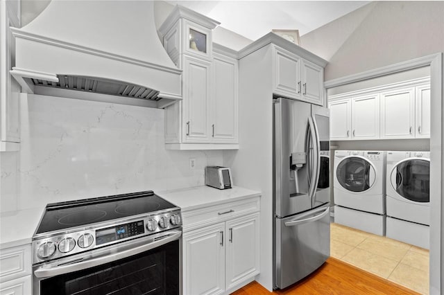 kitchen featuring white cabinets, stainless steel appliances, washer and dryer, and custom range hood