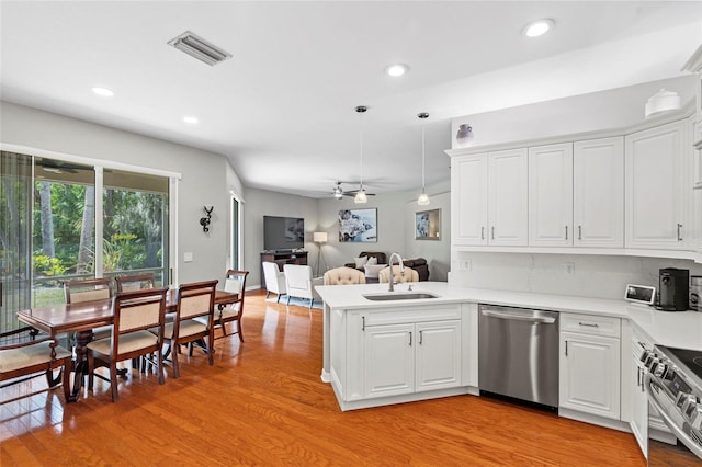 kitchen featuring appliances with stainless steel finishes, open floor plan, a peninsula, light wood-style floors, and a sink