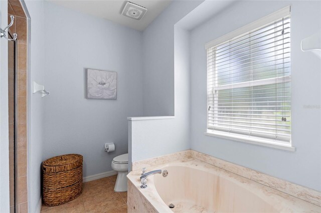 bathroom featuring baseboards, toilet, tile patterned floors, a tile shower, and a bath