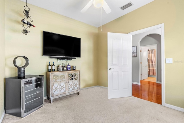 carpeted living room with visible vents, arched walkways, baseboards, lofted ceiling, and ceiling fan