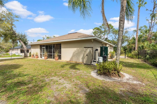 rear view of property with a yard, fence, and stucco siding