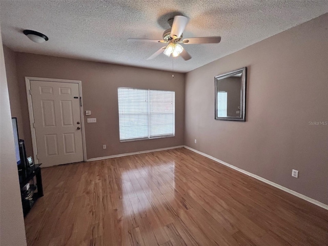 interior space featuring ceiling fan, a textured ceiling, wood finished floors, and baseboards