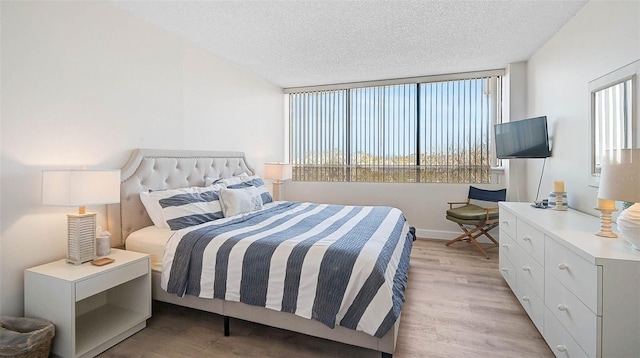 bedroom featuring a textured ceiling, light wood finished floors, and baseboards