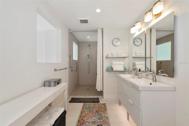 bathroom featuring double vanity, visible vents, a tile shower, a sink, and tile patterned flooring