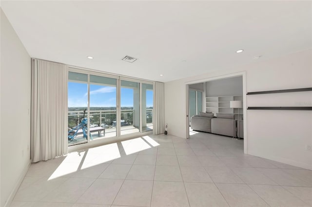 spare room featuring light tile patterned floors, baseboards, visible vents, floor to ceiling windows, and recessed lighting