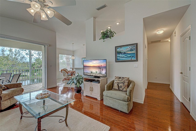 living area with a ceiling fan, wood finished floors, visible vents, and baseboards