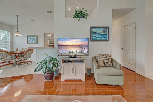 living area with baseboards, wood finished floors, visible vents, and a notable chandelier