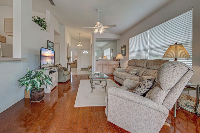 living area with a ceiling fan, visible vents, vaulted ceiling, and wood finished floors