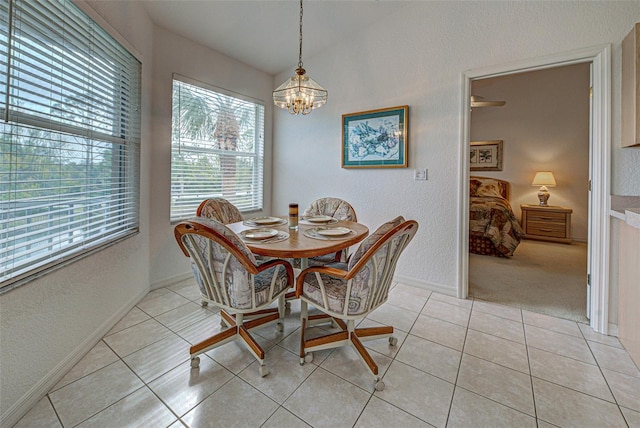 dining space featuring lofted ceiling, an inviting chandelier, a textured wall, and light tile patterned flooring