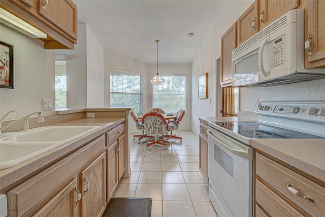 kitchen with white appliances, light countertops, pendant lighting, a sink, and light tile patterned flooring