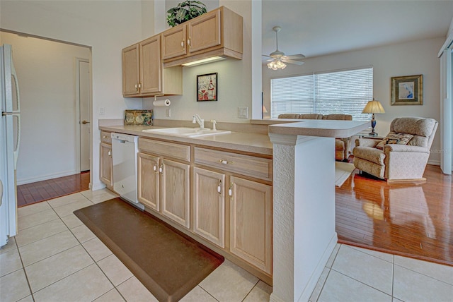 kitchen with light tile patterned flooring, white appliances, a sink, open floor plan, and light brown cabinetry