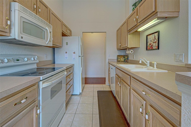 kitchen featuring white appliances, light tile patterned floors, baseboards, light countertops, and a sink