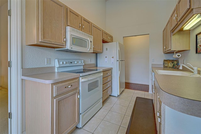 kitchen featuring light countertops, a high ceiling, light tile patterned flooring, a sink, and white appliances