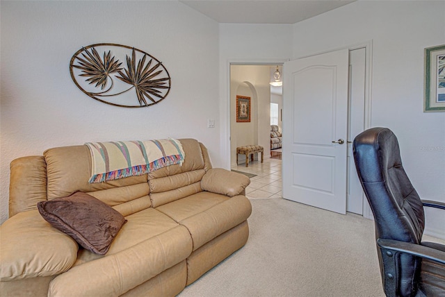 living room with arched walkways, light tile patterned floors, and light colored carpet