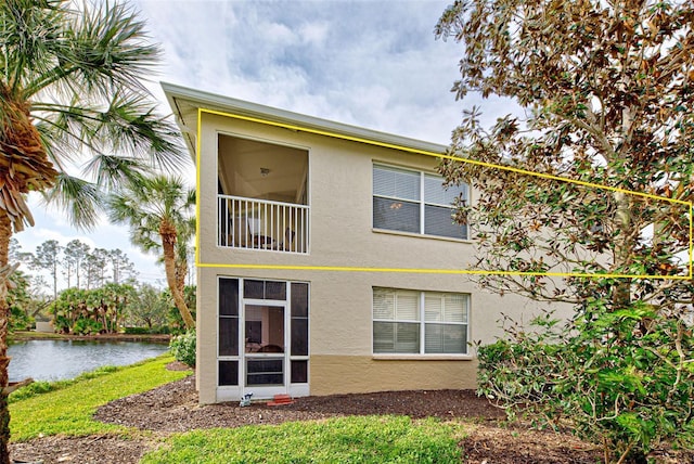 rear view of property featuring a water view and stucco siding