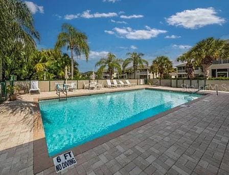 community pool with a patio area and fence