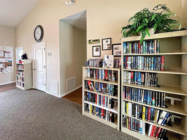 living area with lofted ceiling, baseboards, visible vents, and carpet