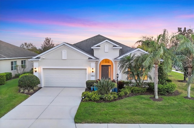 view of front of property featuring concrete driveway, a yard, an attached garage, and stucco siding