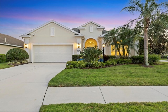 view of front of house with an attached garage, driveway, a lawn, and stucco siding