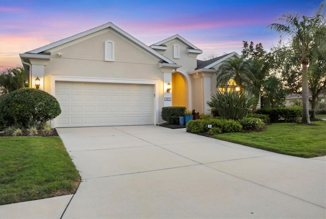 view of front of house featuring a yard, concrete driveway, an attached garage, and stucco siding