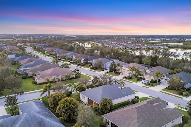 aerial view at dusk with a residential view and a water view