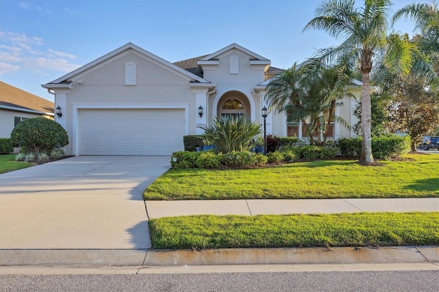 view of front of property featuring a garage, driveway, a front yard, and stucco siding