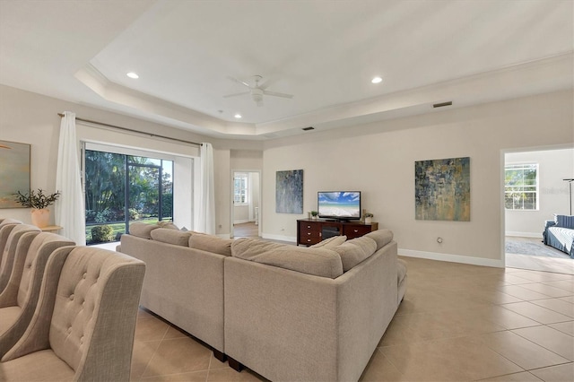 living room featuring a ceiling fan, a raised ceiling, visible vents, and light tile patterned floors