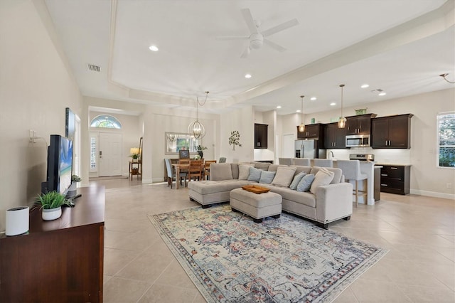 living area featuring light tile patterned floors, recessed lighting, ceiling fan with notable chandelier, visible vents, and baseboards