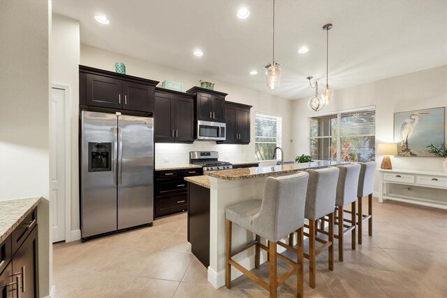 kitchen featuring appliances with stainless steel finishes, backsplash, a breakfast bar, and light stone countertops