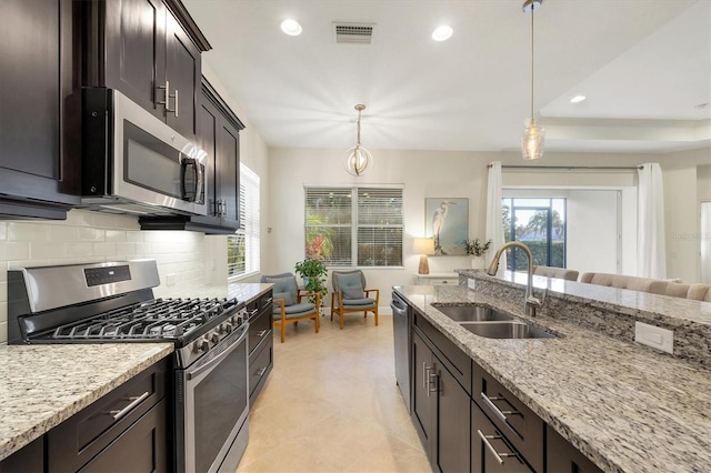 kitchen featuring visible vents, open floor plan, a sink, stainless steel appliances, and backsplash