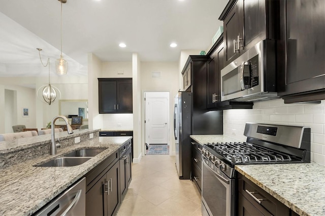 kitchen featuring appliances with stainless steel finishes, decorative backsplash, a sink, and light stone countertops