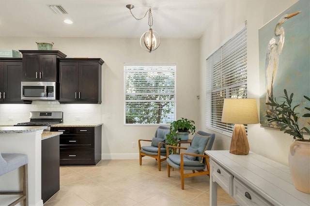 kitchen featuring pendant lighting, visible vents, decorative backsplash, appliances with stainless steel finishes, and baseboards