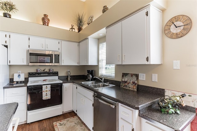 kitchen featuring dark countertops, appliances with stainless steel finishes, dark wood-type flooring, white cabinetry, and a sink