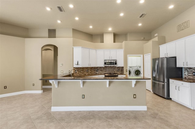 8420 Sailing Loop, Lakewood Ranch, FL 34202 - kitchen with stainless steel appliances, washing machine and dryer, a peninsula, a kitchen bar, and recessed lighting