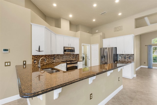8420 Sailing Loop, Lakewood Ranch, FL 34202 - kitchen with stainless steel appliances, a sink, a peninsula, a kitchen breakfast bar, and washer / clothes dryer