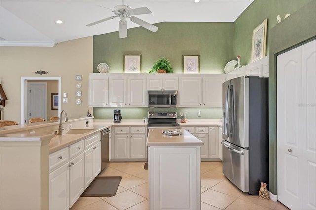 kitchen featuring light countertops, appliances with stainless steel finishes, white cabinets, a sink, and a kitchen island