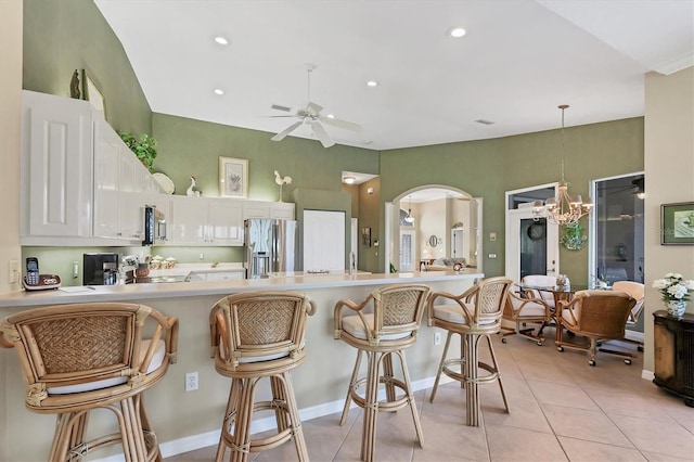 kitchen featuring arched walkways, light tile patterned floors, a peninsula, light countertops, and appliances with stainless steel finishes