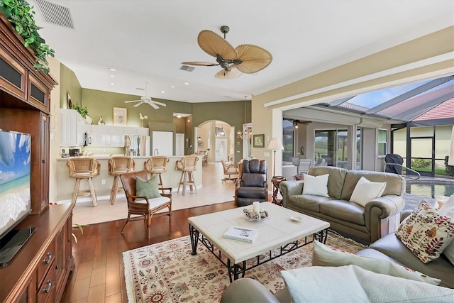 living area with a ceiling fan, arched walkways, visible vents, and wood finished floors