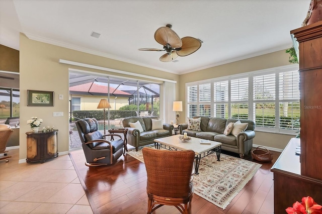 living room featuring baseboards, a sunroom, a ceiling fan, and crown molding