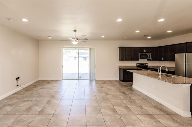 kitchen featuring light stone counters, recessed lighting, appliances with stainless steel finishes, a sink, and baseboards