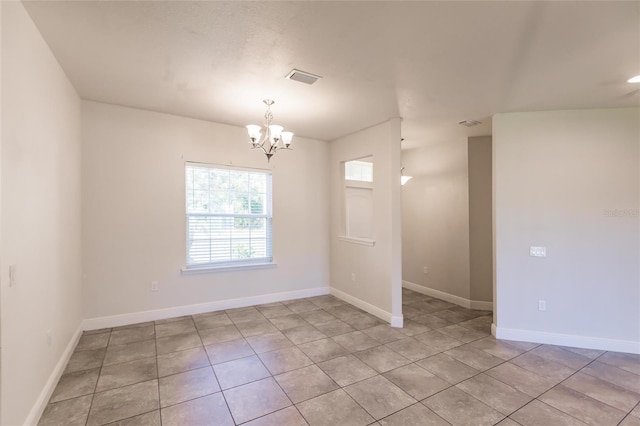 unfurnished room with an inviting chandelier, visible vents, baseboards, and light tile patterned flooring